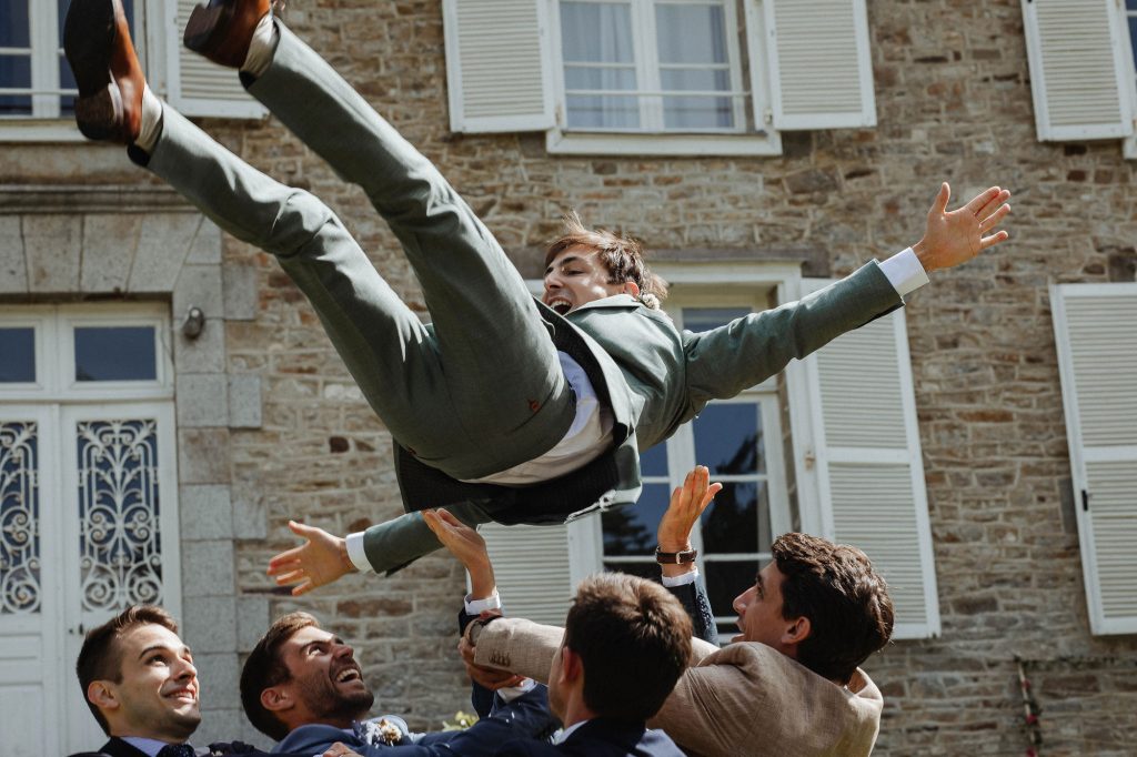 marié dans les airs pendant les photos de groupe lors d'un mariage à Vitré