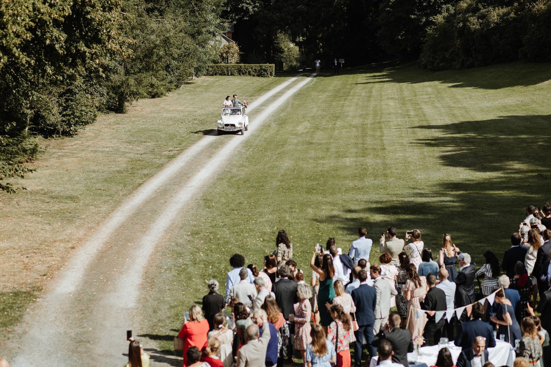 voiture des mariés arrivent devant les invités dans une domaine de Bretagne